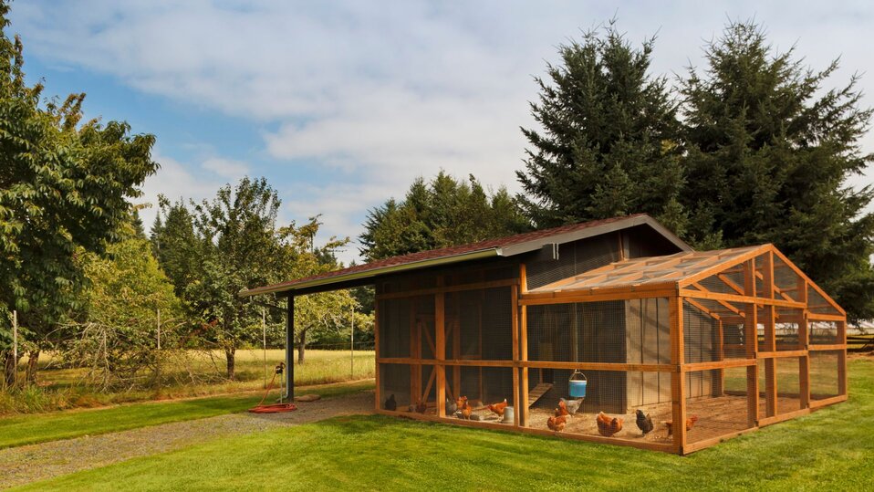 A large chicken coop with a fenced in run.