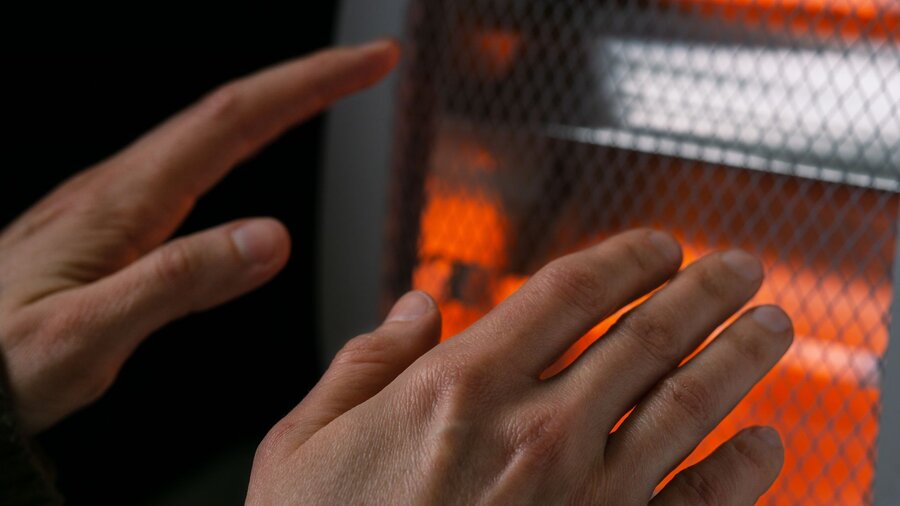 A person warming their hands next to a heater in their garage.
