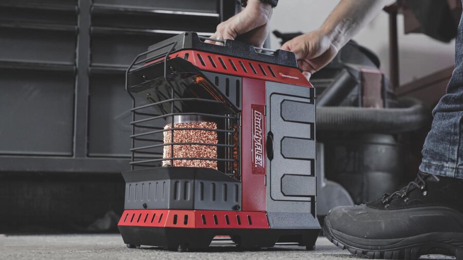 A man placing a Mr. Heater Flex on the floor of his barn.