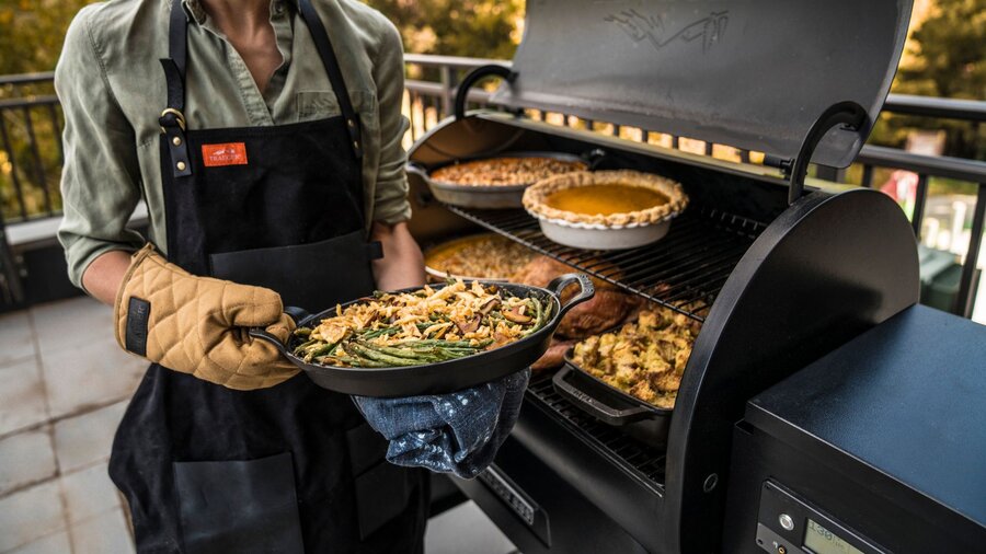 A woman in front of her BBQ grill cooking Thanksgiving dinner.