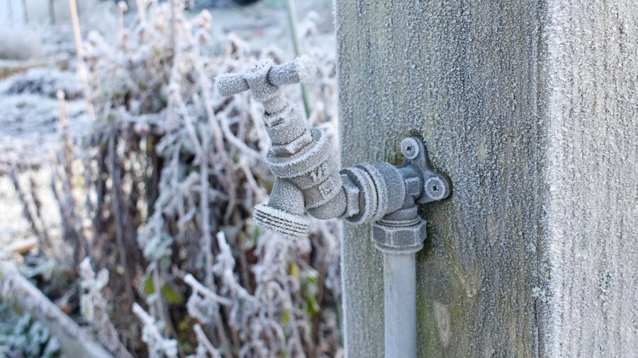 An outdoor faucet covered with frost after the first cold winter snap.