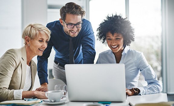 Professionals collaborating around a laptop
