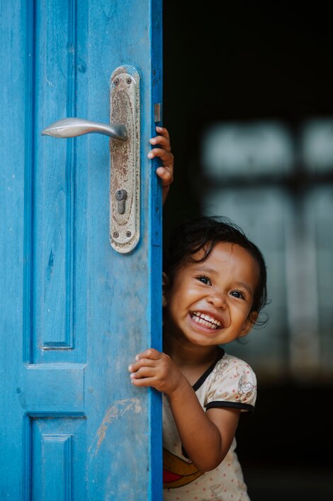 a child playfully posing from behind an open door