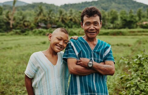 father and son standing in front of their field