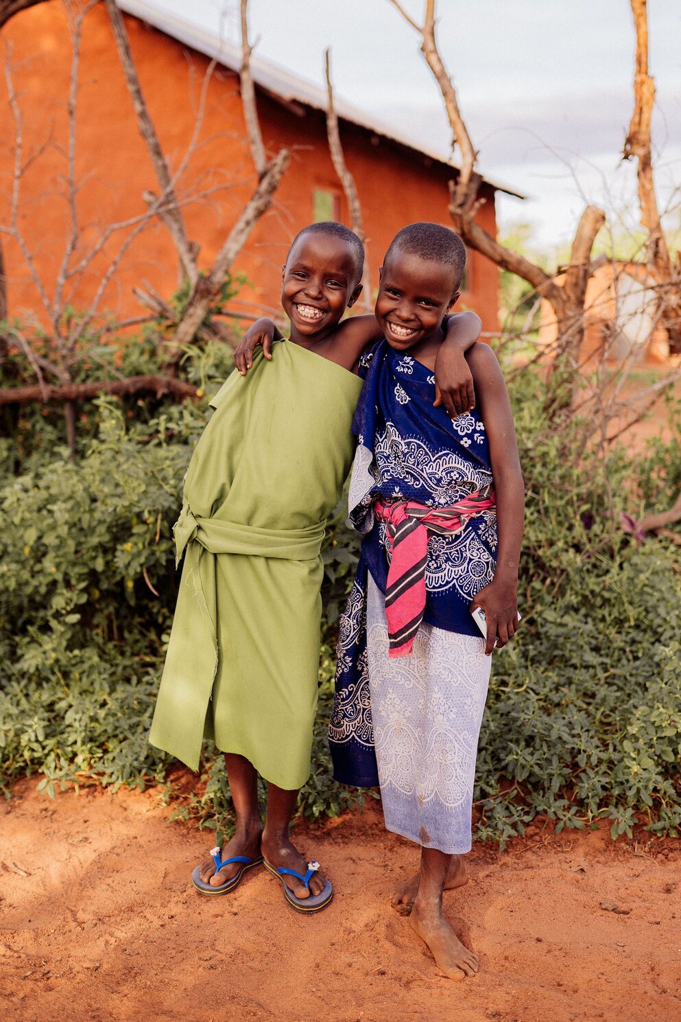 two children smiling with their arms around each others' shoulders