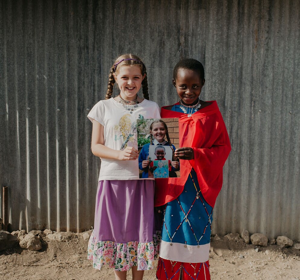Students holding booklets and smiling outdoors