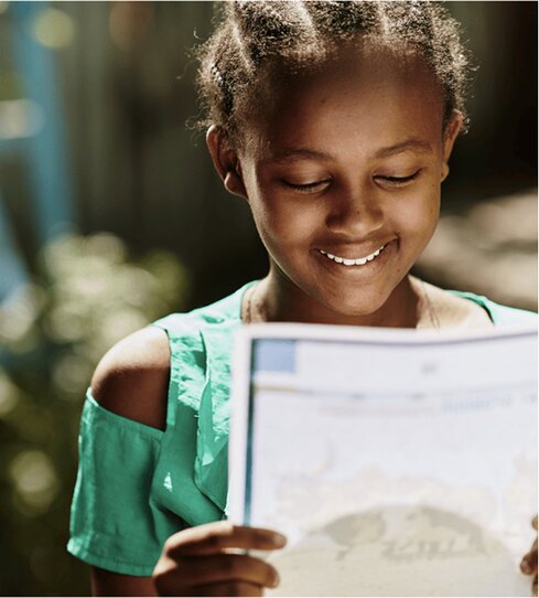 girl smiling while reading a letter