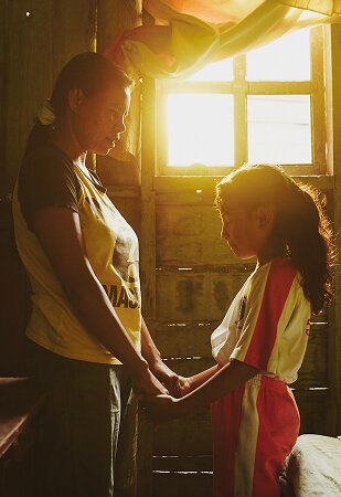 mother and daughter holding hands and praying