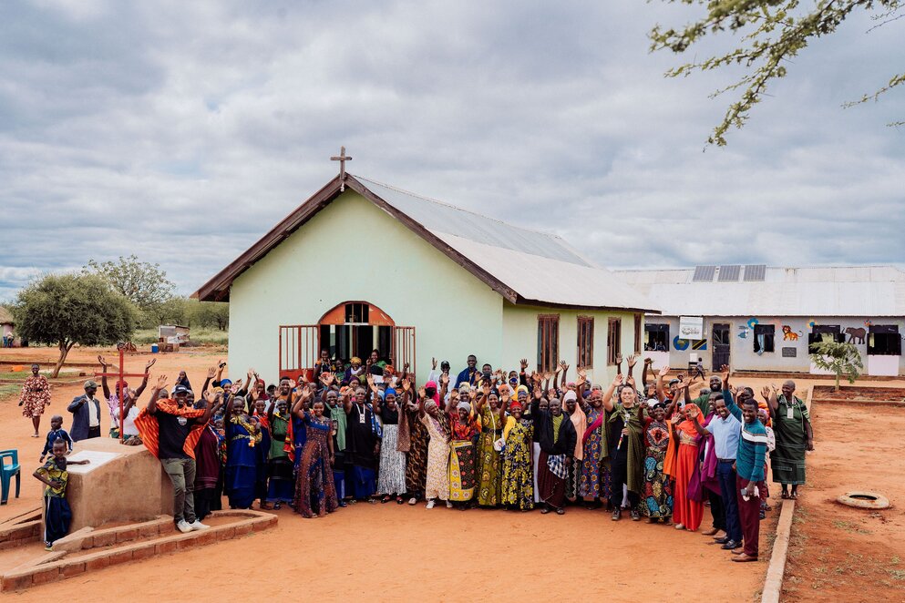 a group of people waving joyfully in front of a church building