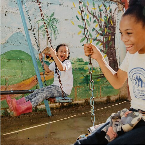 two girls happily playing on swings