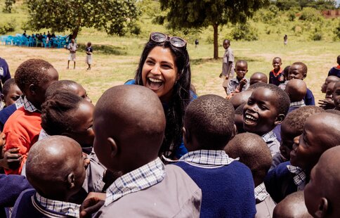 a group of happy children surrounding a guest visitor