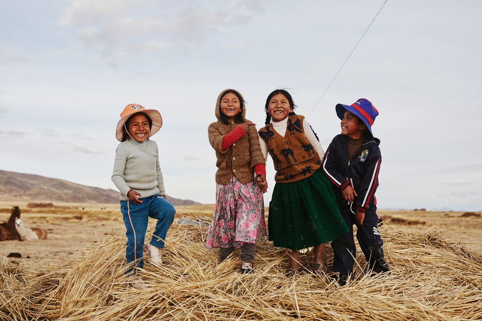 photo of Bolivian children standing on a mound of hay