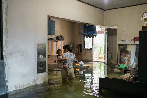 a woman wading in flood waters holding a baby