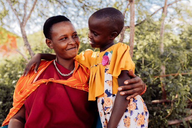 Upendo and her mother smiling and embracing one another