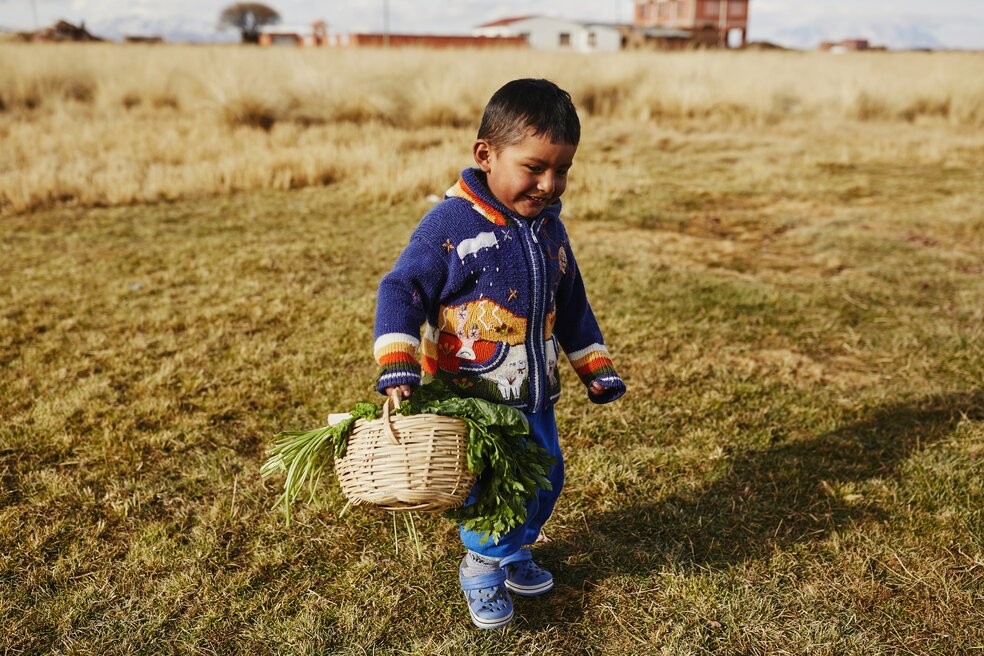 photo of Bolivian children holding a basket of vegetables