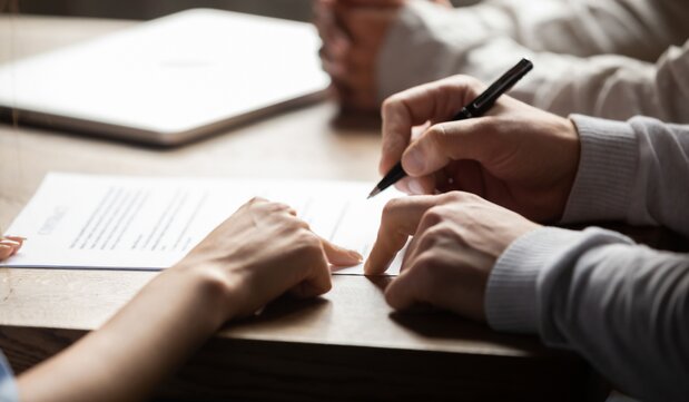 Person signing documents on a desk