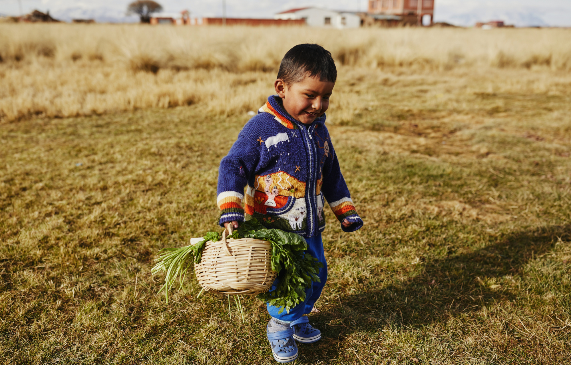 a young boy holding a basket of veggies