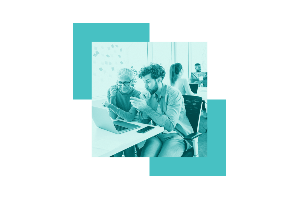 A man and woman looking at a computer while the woman holds a phone to her ear.