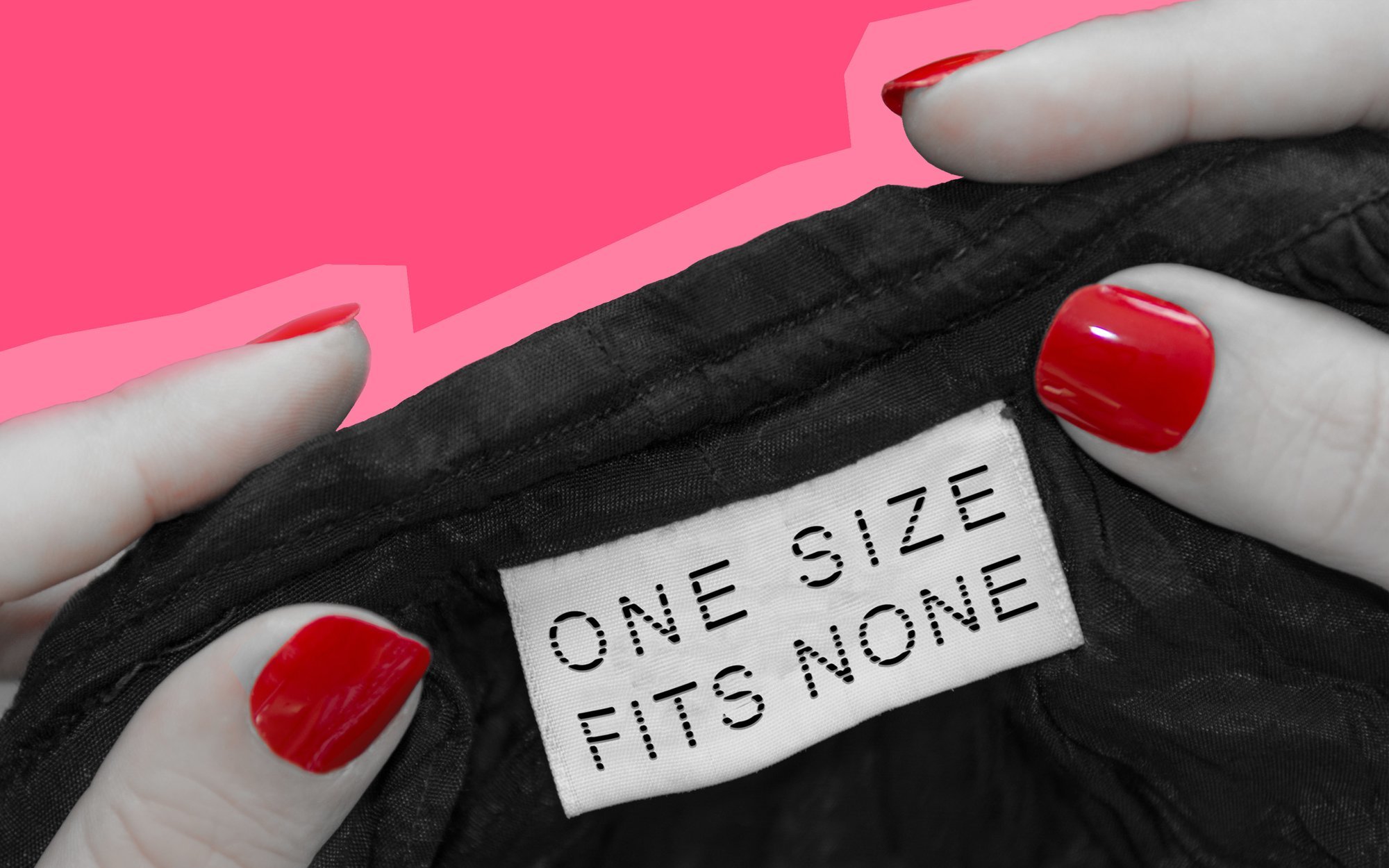 A black and white photo close up of a pair of hands with red nail polish showing the label from a garment that reads “One size fits none”.