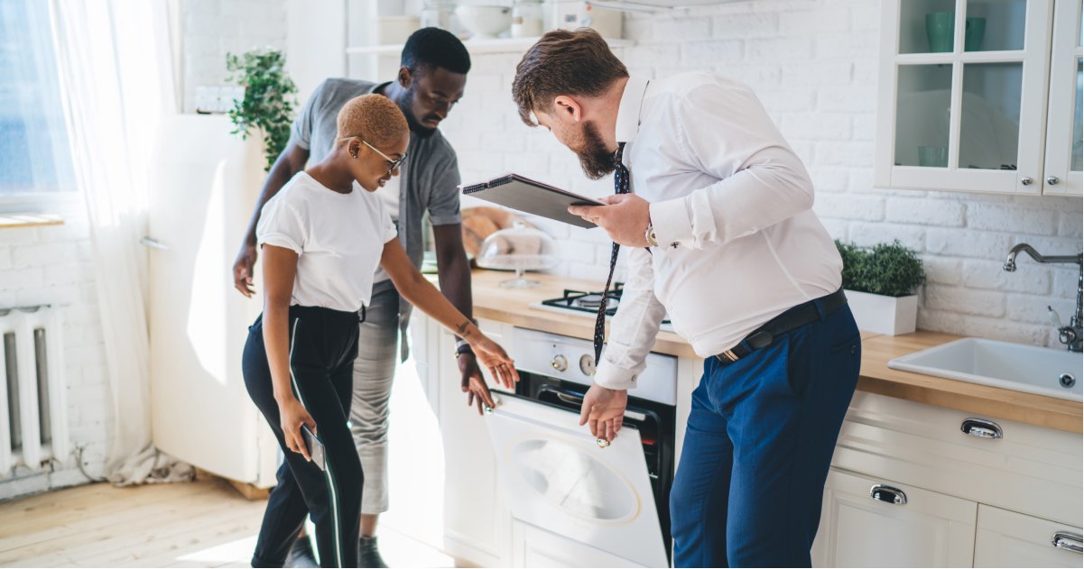 Three Persons Inspecting Oven in Modern Kitchen