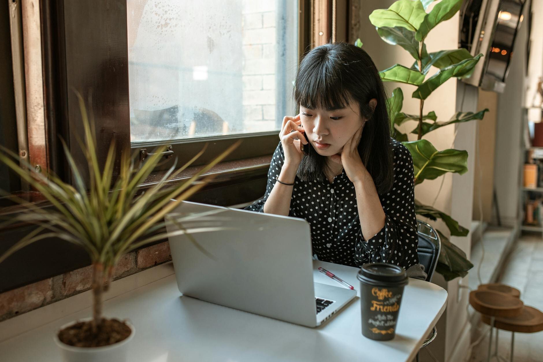 Young woman on her laptop in a coffee shop, learning the options she has regarding getting a HELOC for her investment property