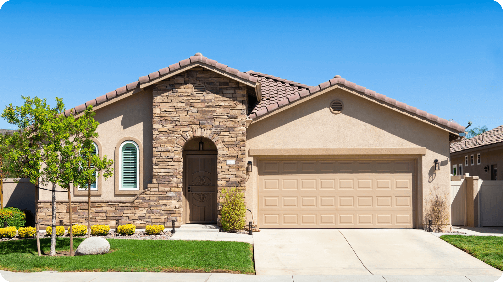 Single-story suburban home with a stone facade, two-car garage, and neatly landscaped front yard.