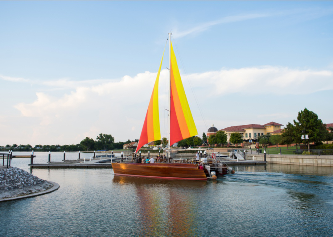 “Photograph of a sailboat with colorful sails on a small lake” - Source: Alissala // Shutterstock