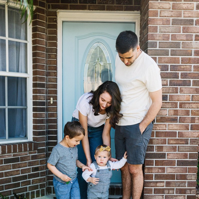 Better Mortgage Clients, Carly and Michael with Their Young Children Outside of Their Brick Home