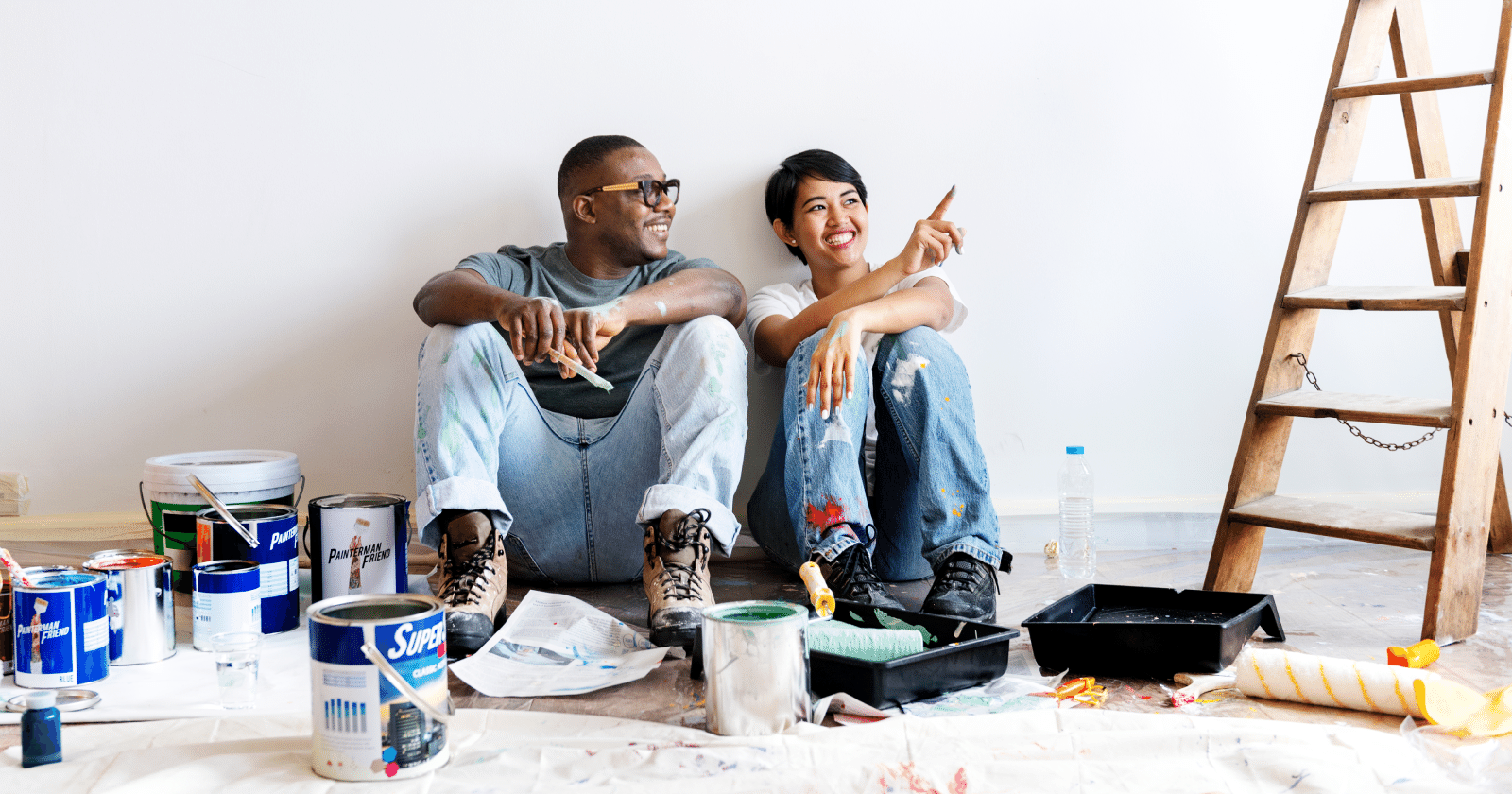 Two People Sitting Between Cans of Paint and a Ladder
