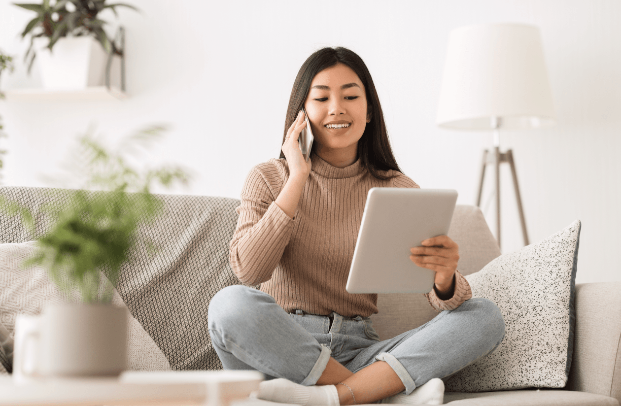 Person Smiling On the Phone Reviewing Notepad in Bright Living Room