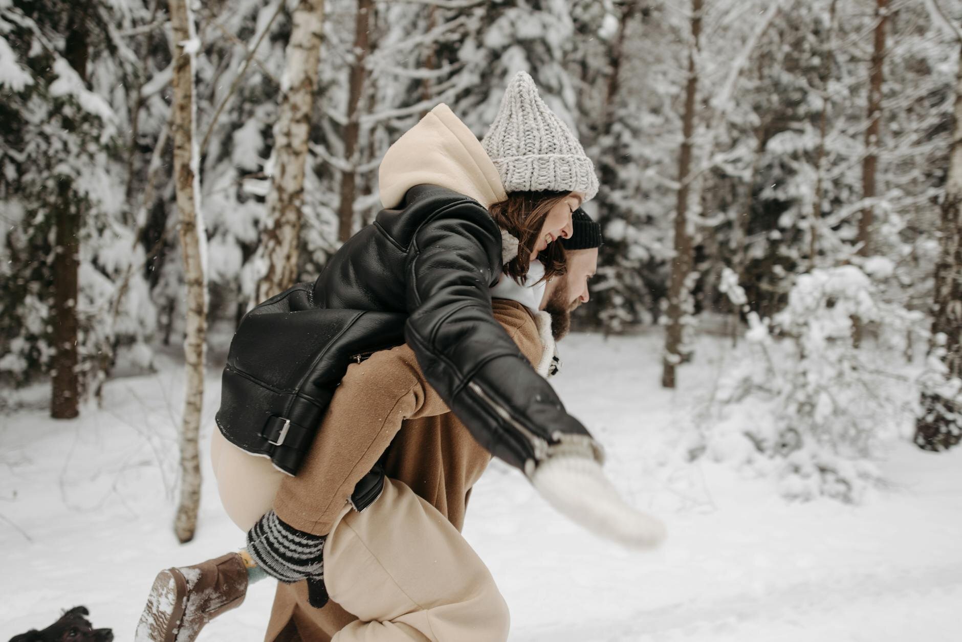 Person giving another person a piggyback ride through a snowy forest, visually symbolizing the concept of a ‘piggyback’ loan — where one loan supports another.