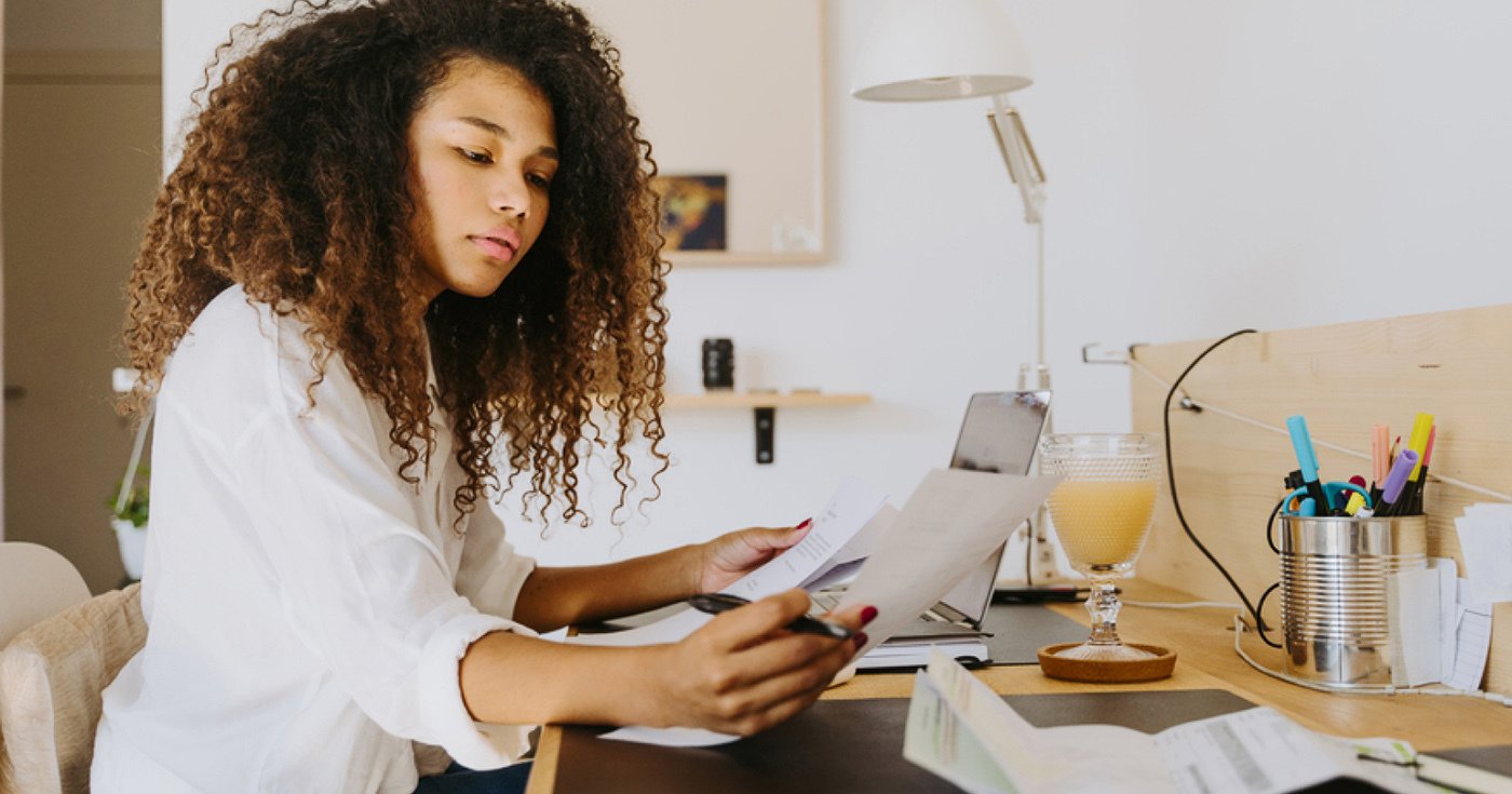 Person Sitting at Desk with Laptop Reviewing Documents