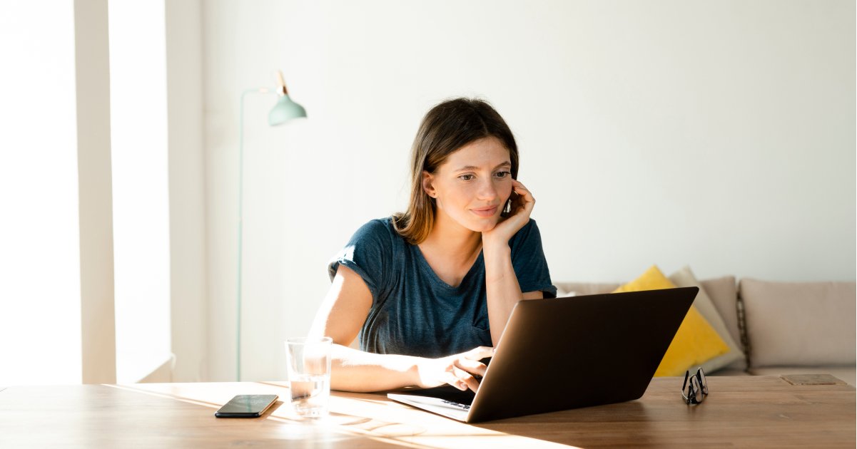 Young Person Seated at Wooden Table Looking at Laptop