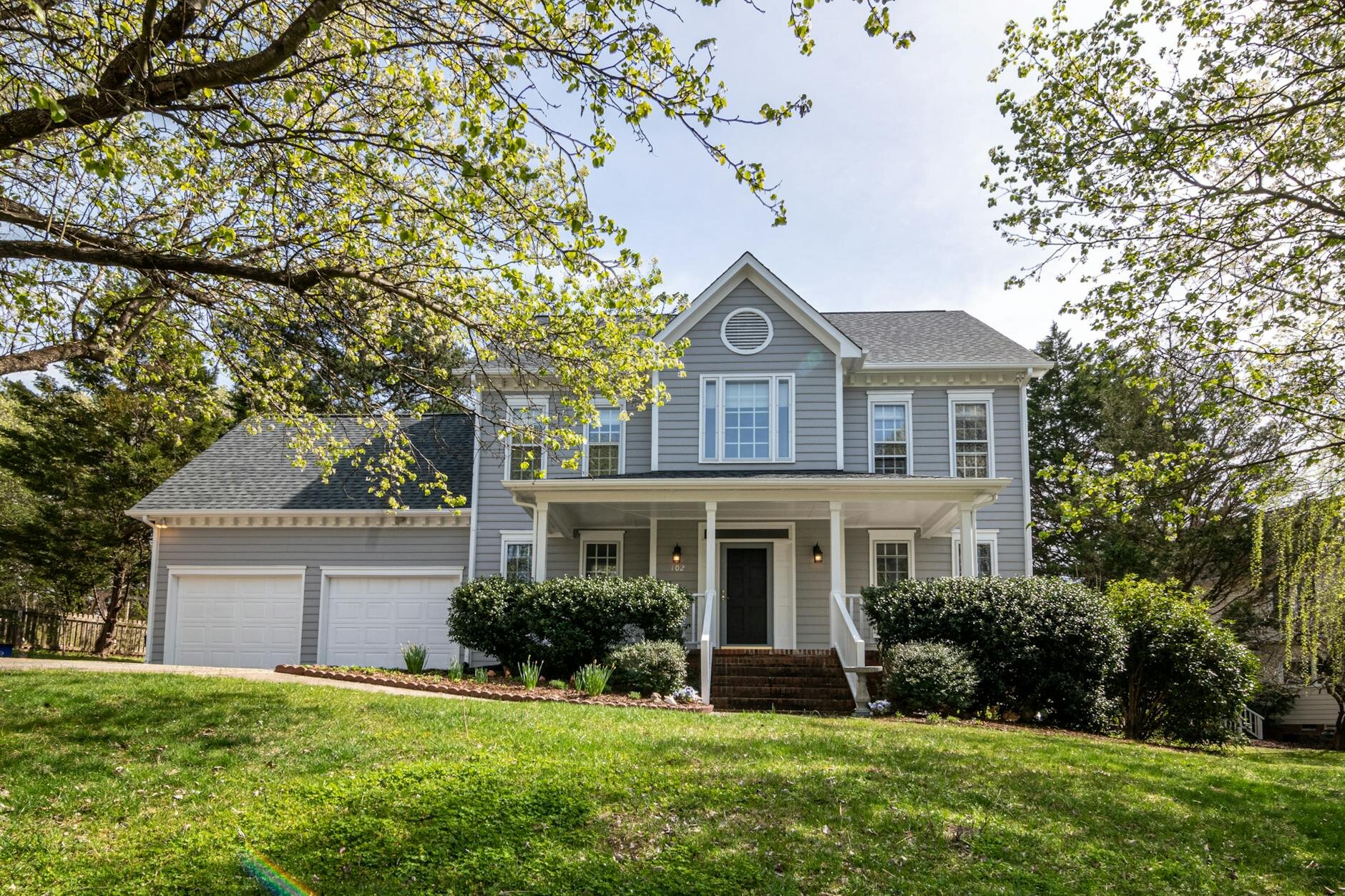 Front view of a well-kept suburban home with manicured lawn and blue sky — representing stability amid questions like &#39;Will the housing market crash in 2025?