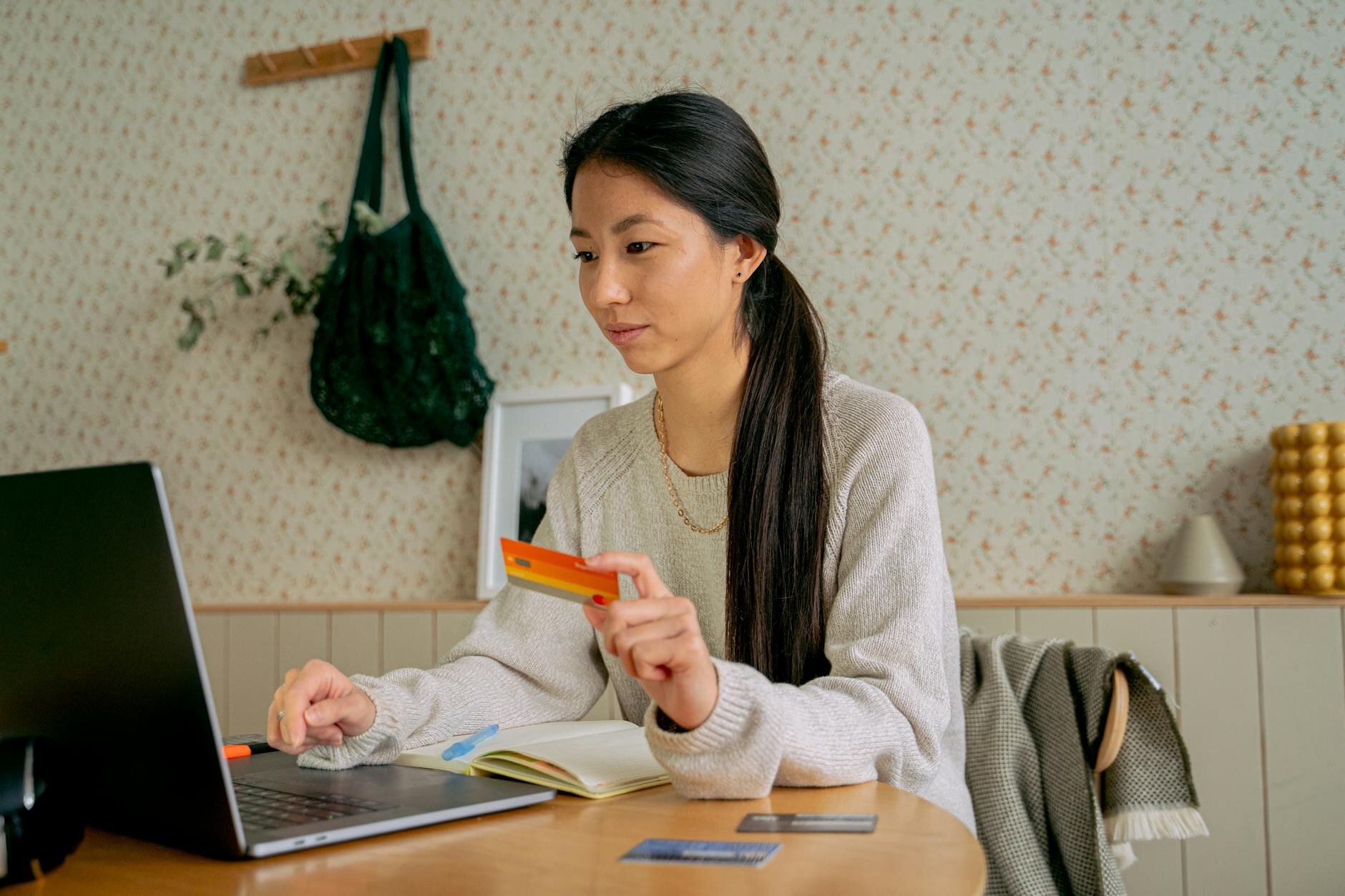 Homeowner reviewing finances online while holding a credit card at her home computer