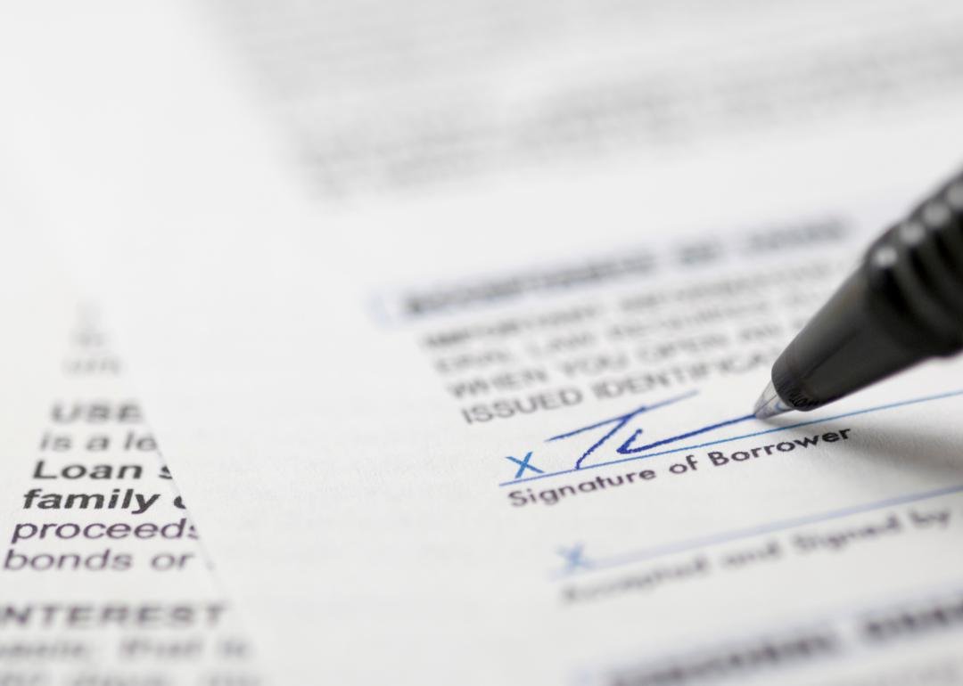 “Photograph of a pen applying a signature to a mortgage document” - Source: Canva