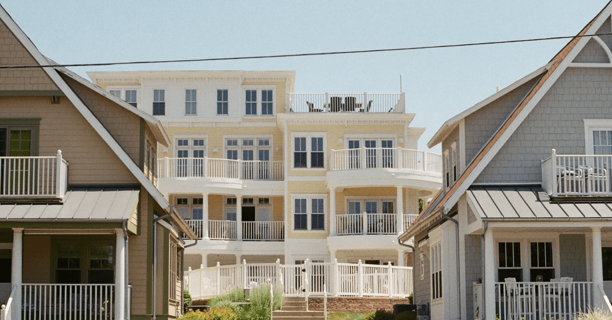 Two Beach Style Homes in Foreground with Larger Light Yellow Beach Style Home in Between Them in Background