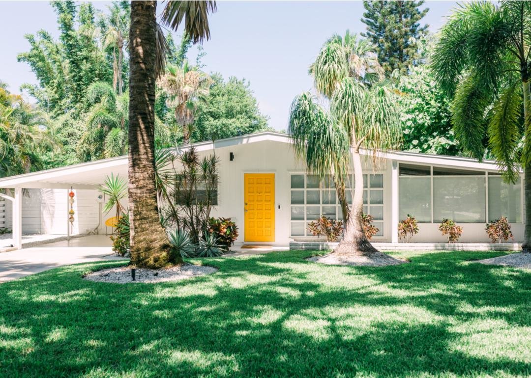 Ranch-style home with yellow door surrounded by palm trees - Source: Karen Culp // Shutterstock