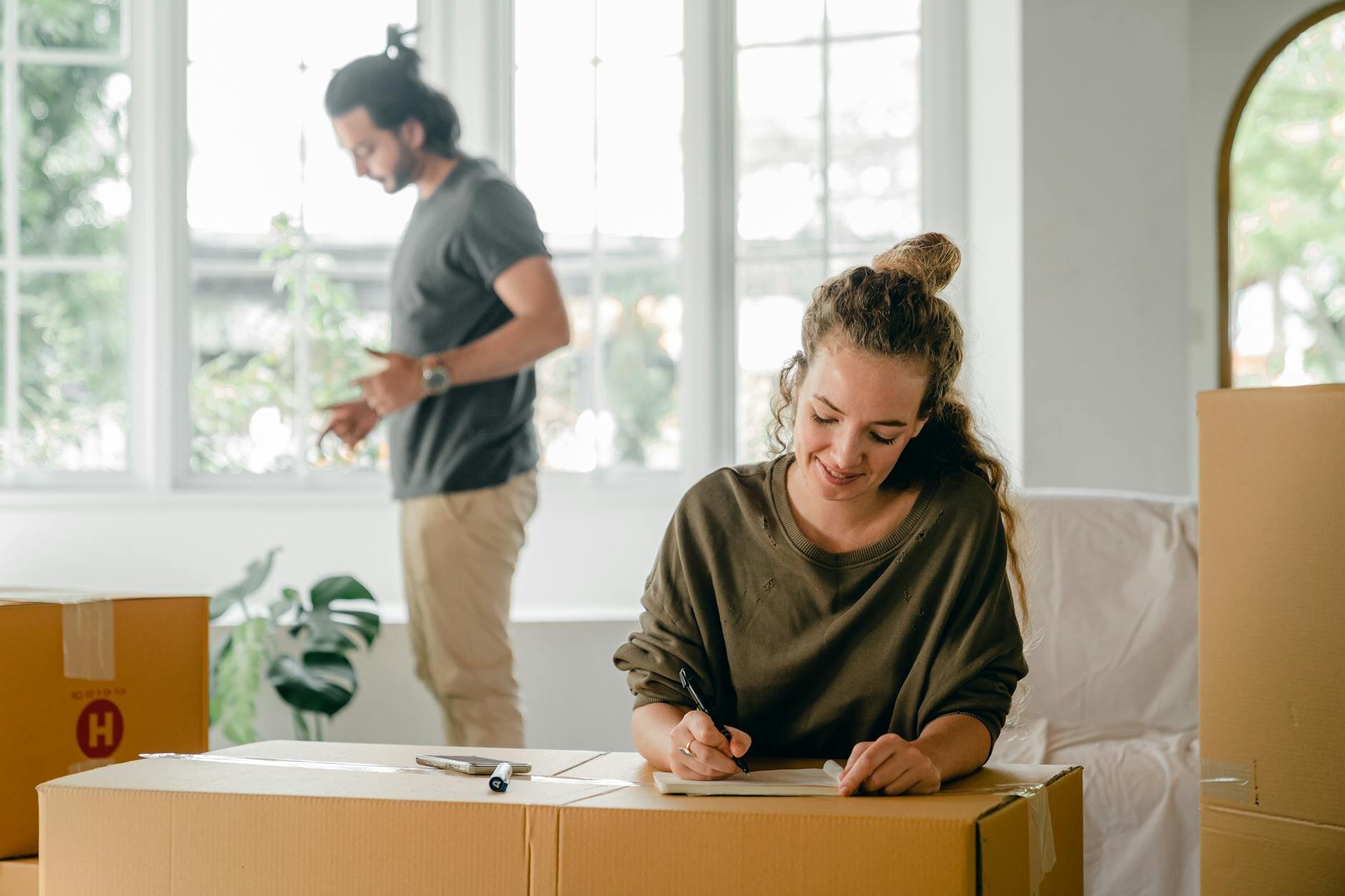Couple unpacking boxes in their new home after buying with plans to refinance when mortgage rates fall.