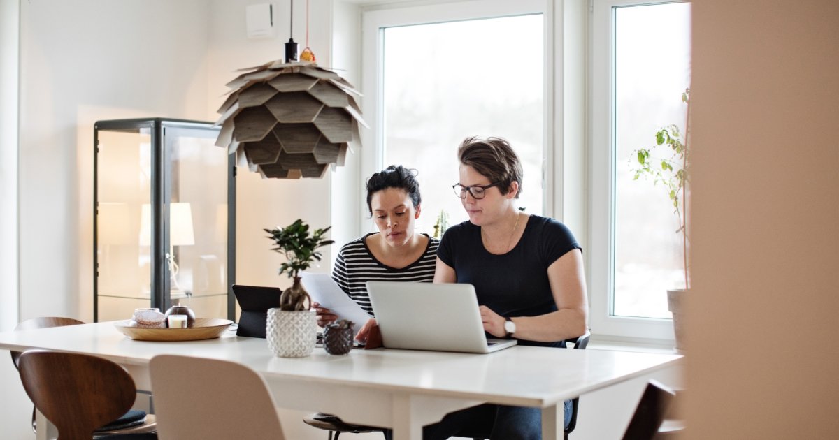 Two Persons with Laptop Reviewing Documents in a Stylish Living Room