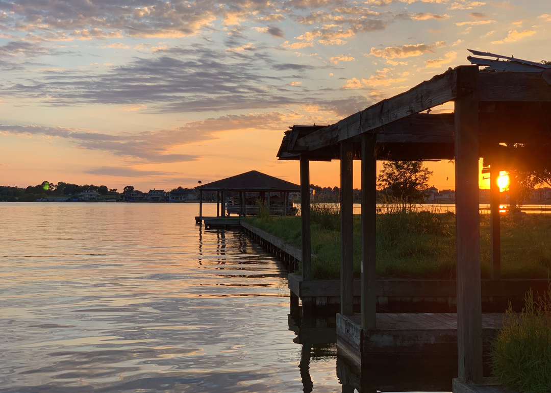 “Photograph of a sunset over water, with a pier and boathouse visible” - Source: Sonja Botes // Shutterstock