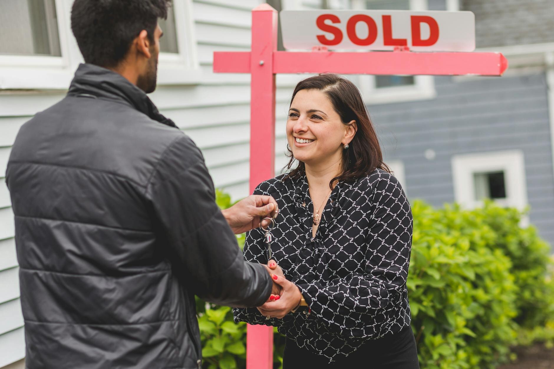 A buyers agent hands over the keys to the home's buyer after a successful transaction.
