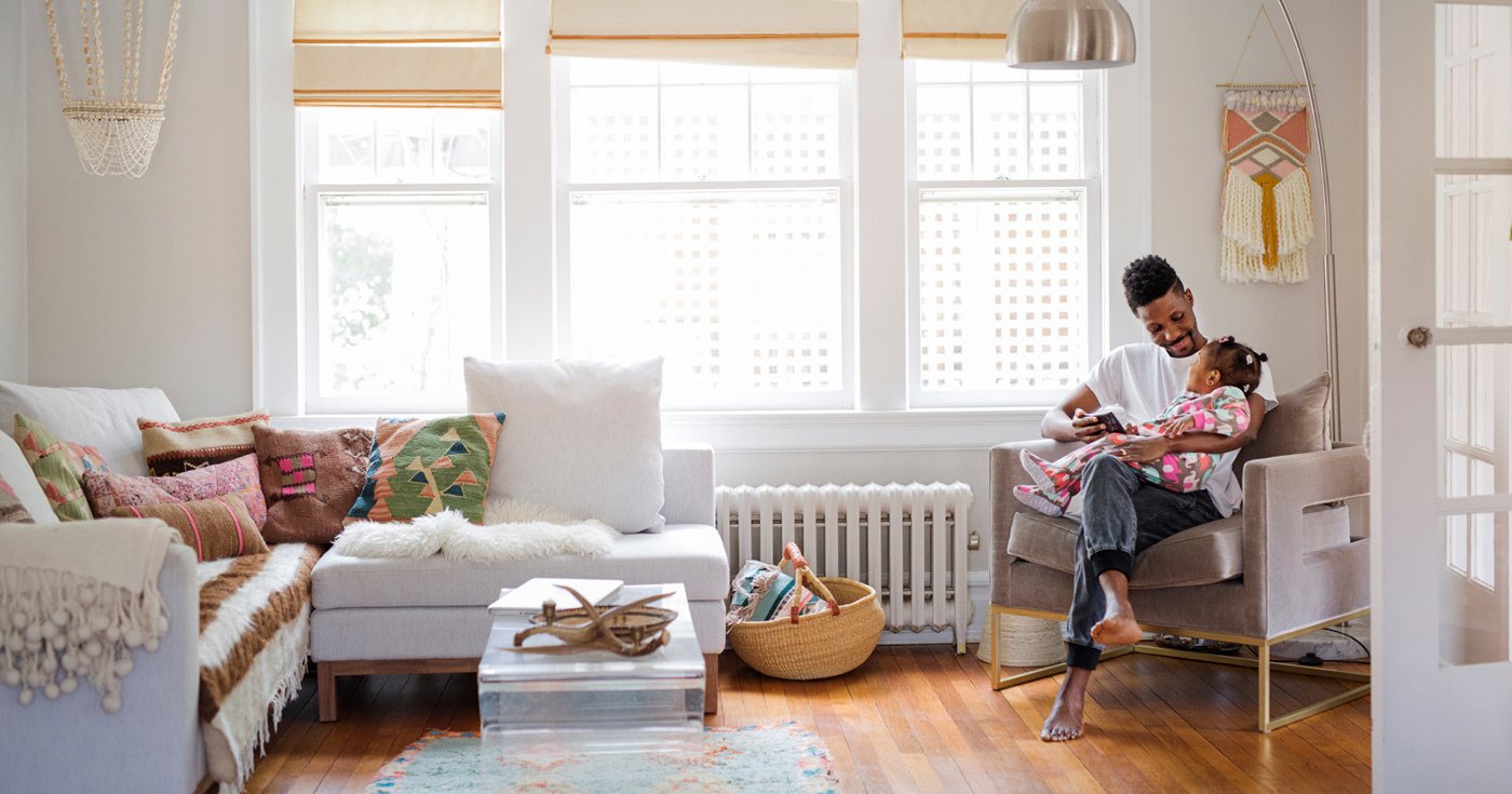 Person Holding and Smiling at Toddler in Chair Placed in Corner of Stylish Living Room