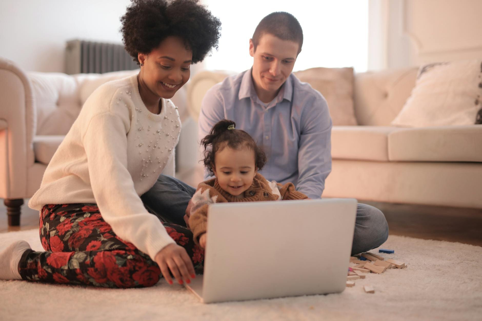 Young couple with child reviewing finances on laptop at home, researching what percentage of income should go to mortgage.