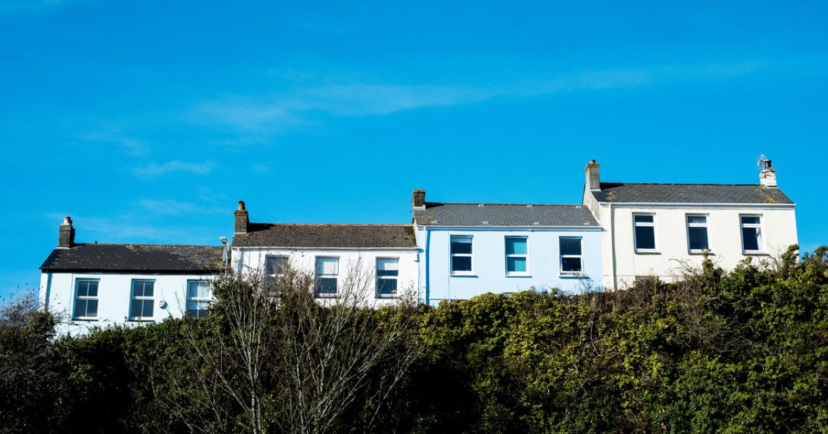 Four Tiered Pastel Colored Homes and Greenery Against Clear Blue Sky