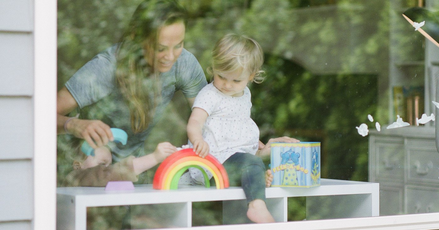 Mother and Toddler Sitting on Low Table Playing With a Toy Rainbow