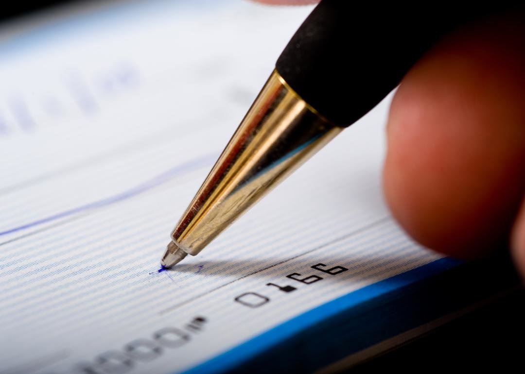  “Close-up photograph of the tip of a pen poised to sign a check” - Source:Canva