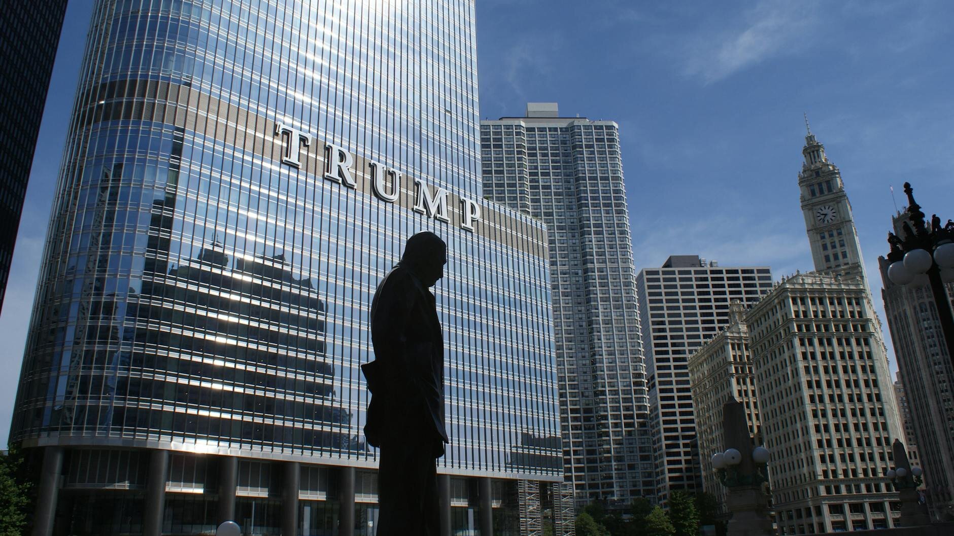 Man standing in front of Trump-branded real estate, symbolizing the impact of Donald Trump’s trade policies on mortgage rates and the housing market.