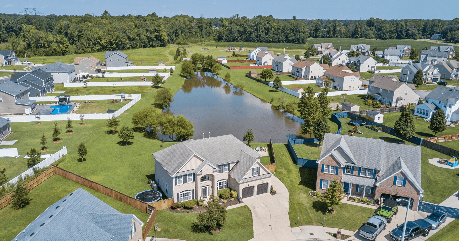Aerial View of Suburban Houses Circling Around A Pond