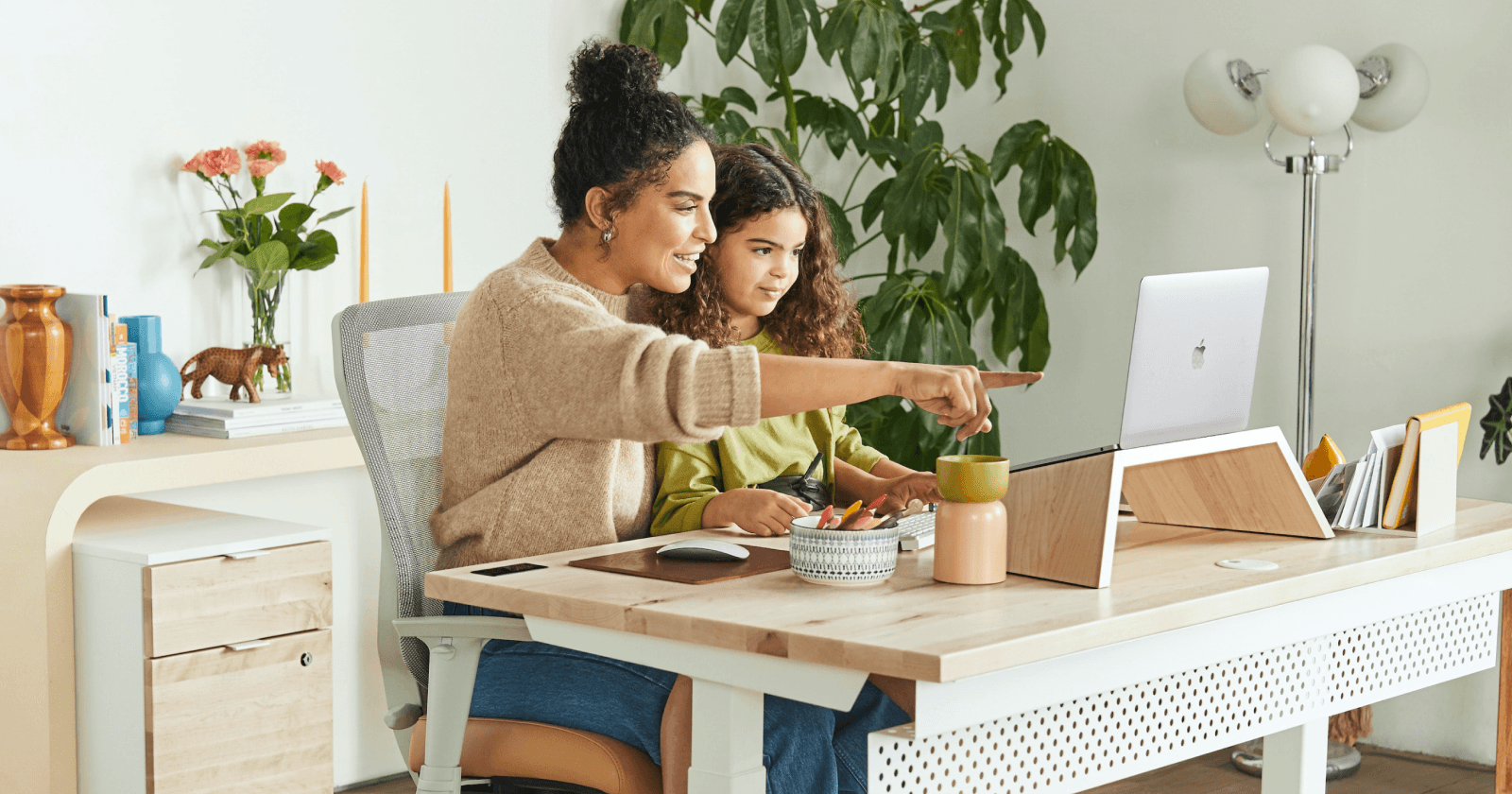 Mother Figure with Child Pointing to Laptop in Modern Office Setting